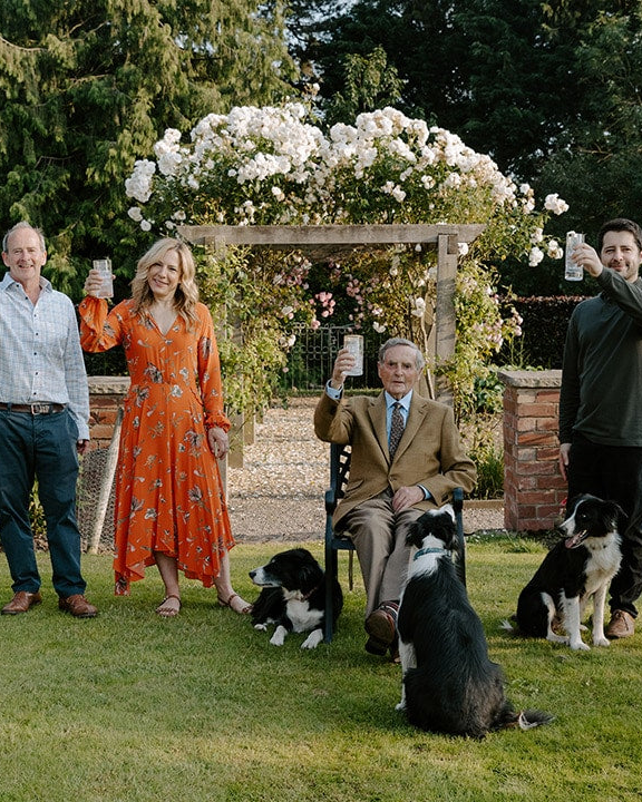 Three generations of the Foreva Farmers family raising a glass in the farm garden with their sheepdogs